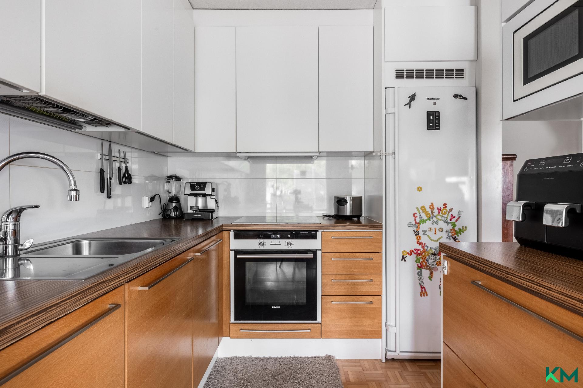 Tyylikkäässä ja modernissa keittiössä hyvin kaapistoja ja pöytäalaa.