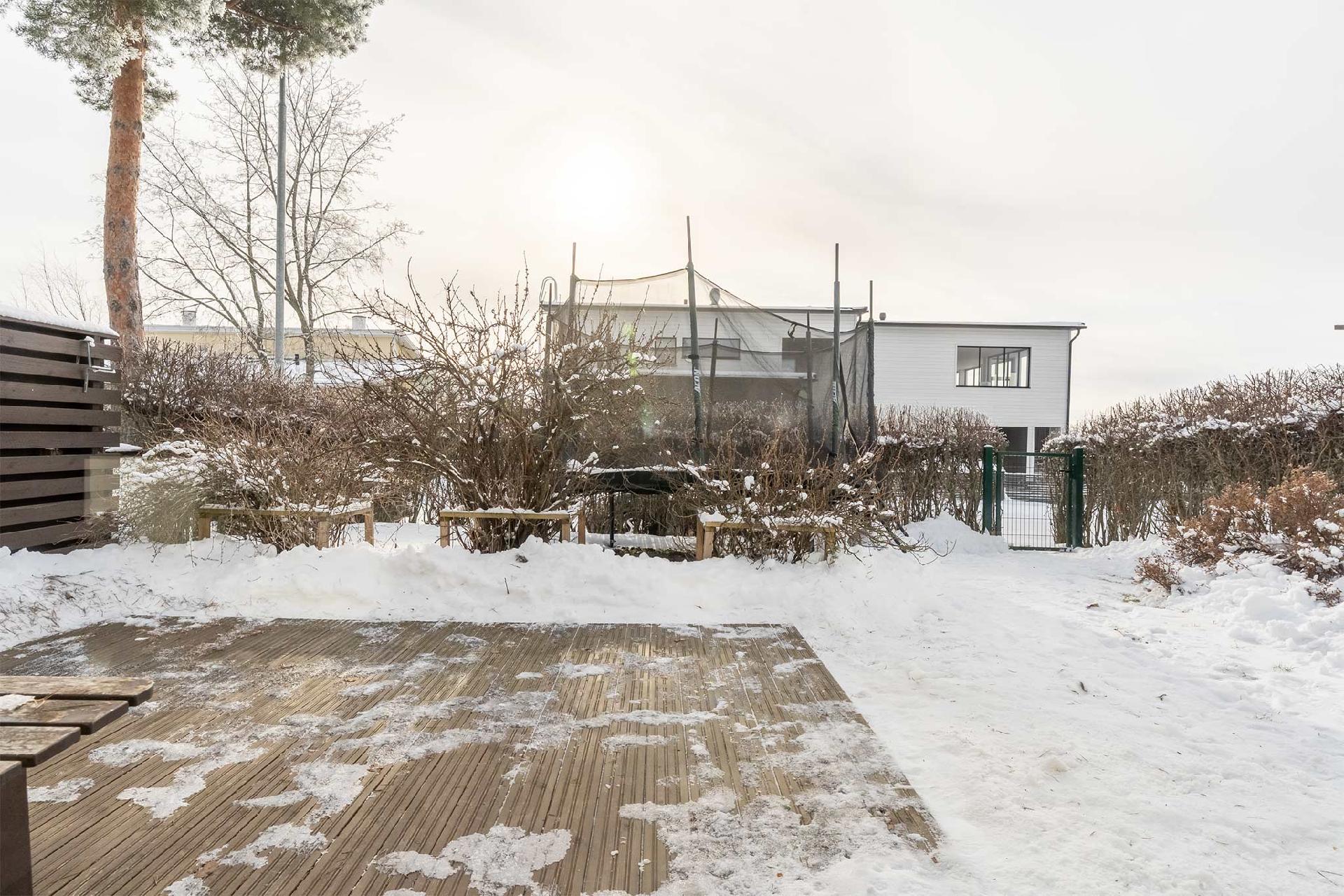Kivan kokoinen terassi ja marjapensaita, tilaa esimerkiksi trampoliinille. Talojen välistä pilkottaa Pyhäjärvi.