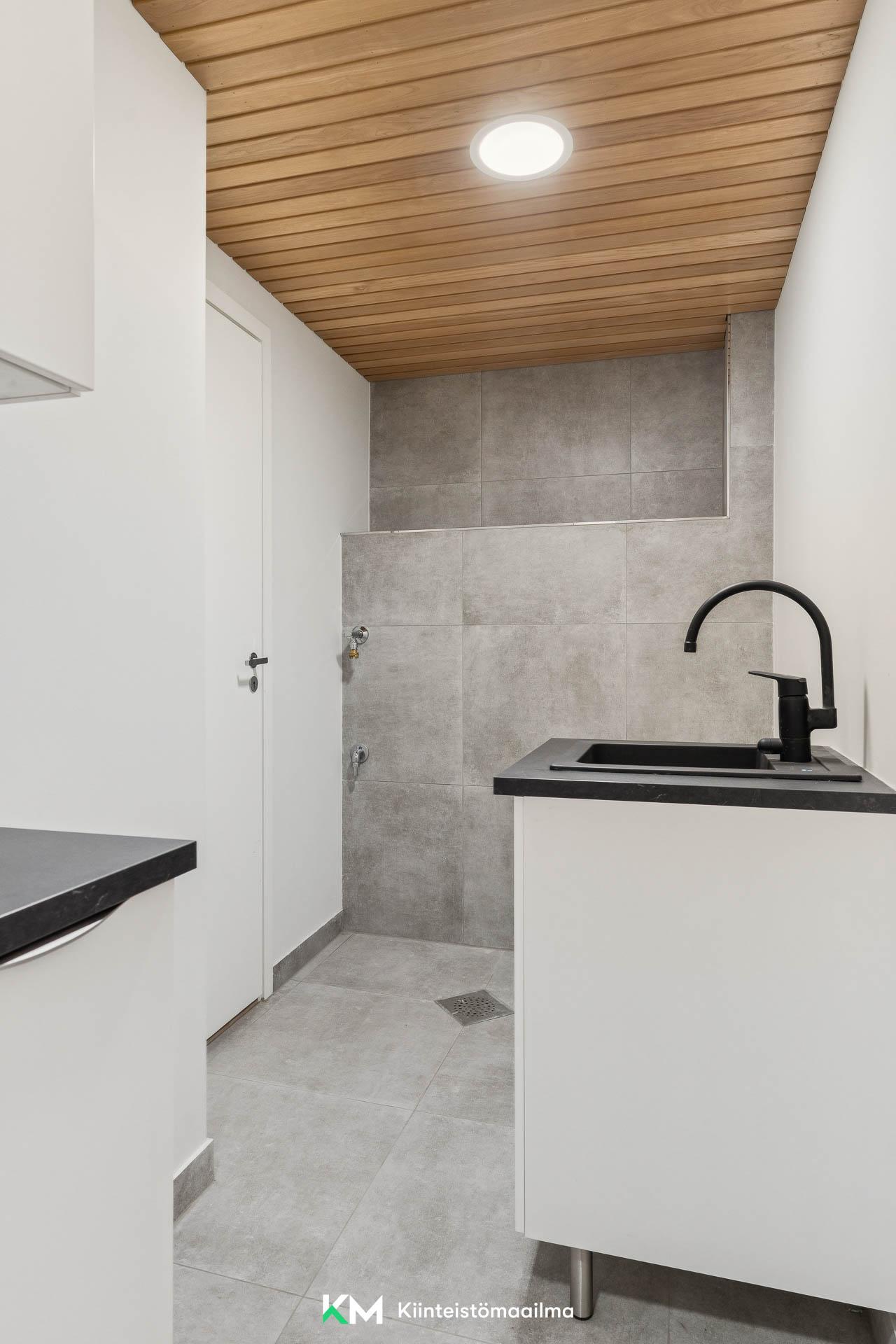 Kodinhoitohuone sijaitsee kellarikerroksessa. Tilaa on niin pyykinpesukoneelle kuin kuvausrummulle kätevästi vierekkäin sijoitettuna.