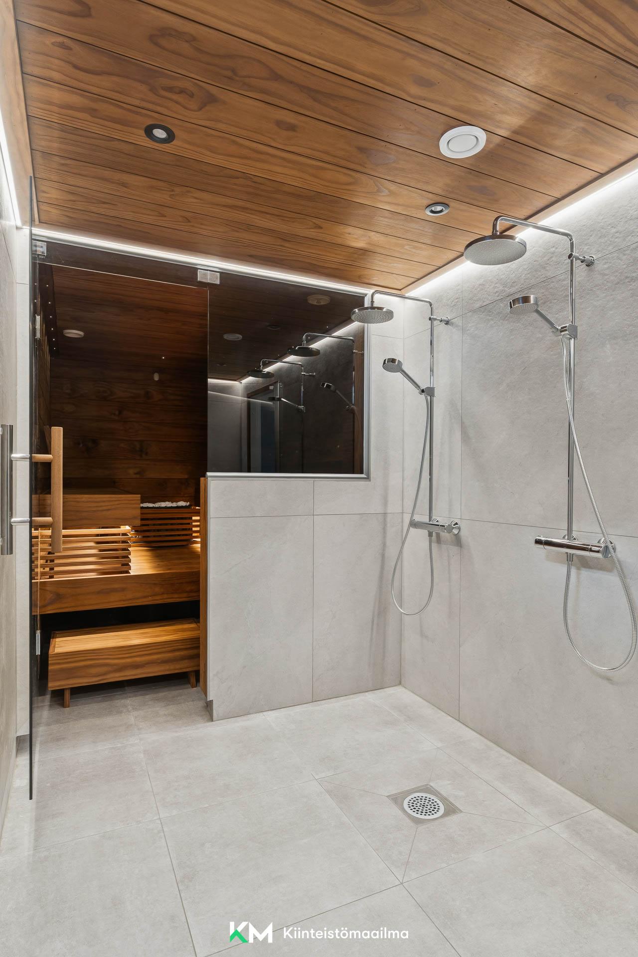 Saunassa on SPA-tunnelmaa epäsuoran valaistuksen ansiosta. Kaksi sadesuihkua helpottaa arkea.
