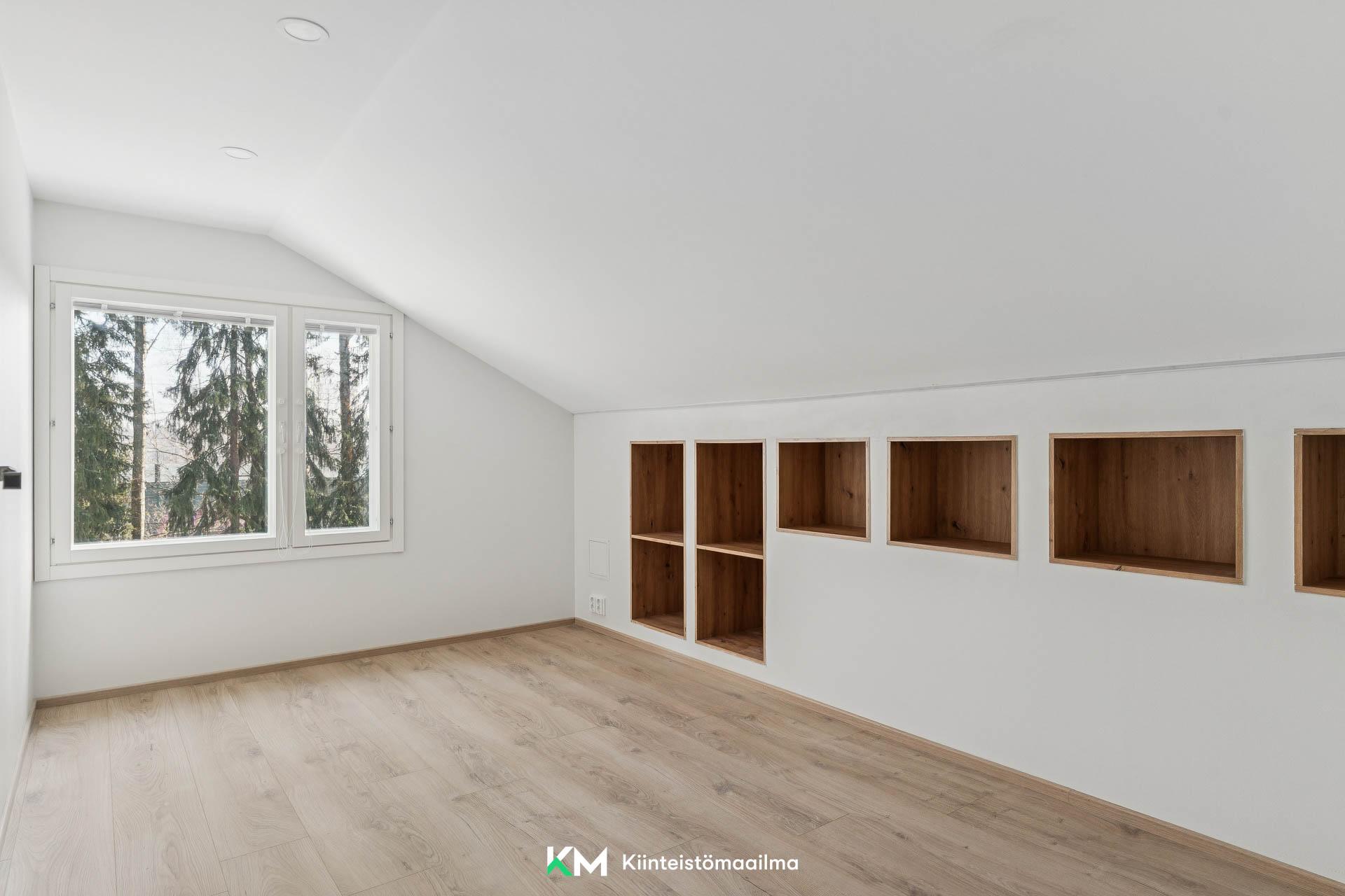 Yläkerran toinen, pieni makuuhuone. Matalaan tilaan on upotettu kätevät hyllyt.