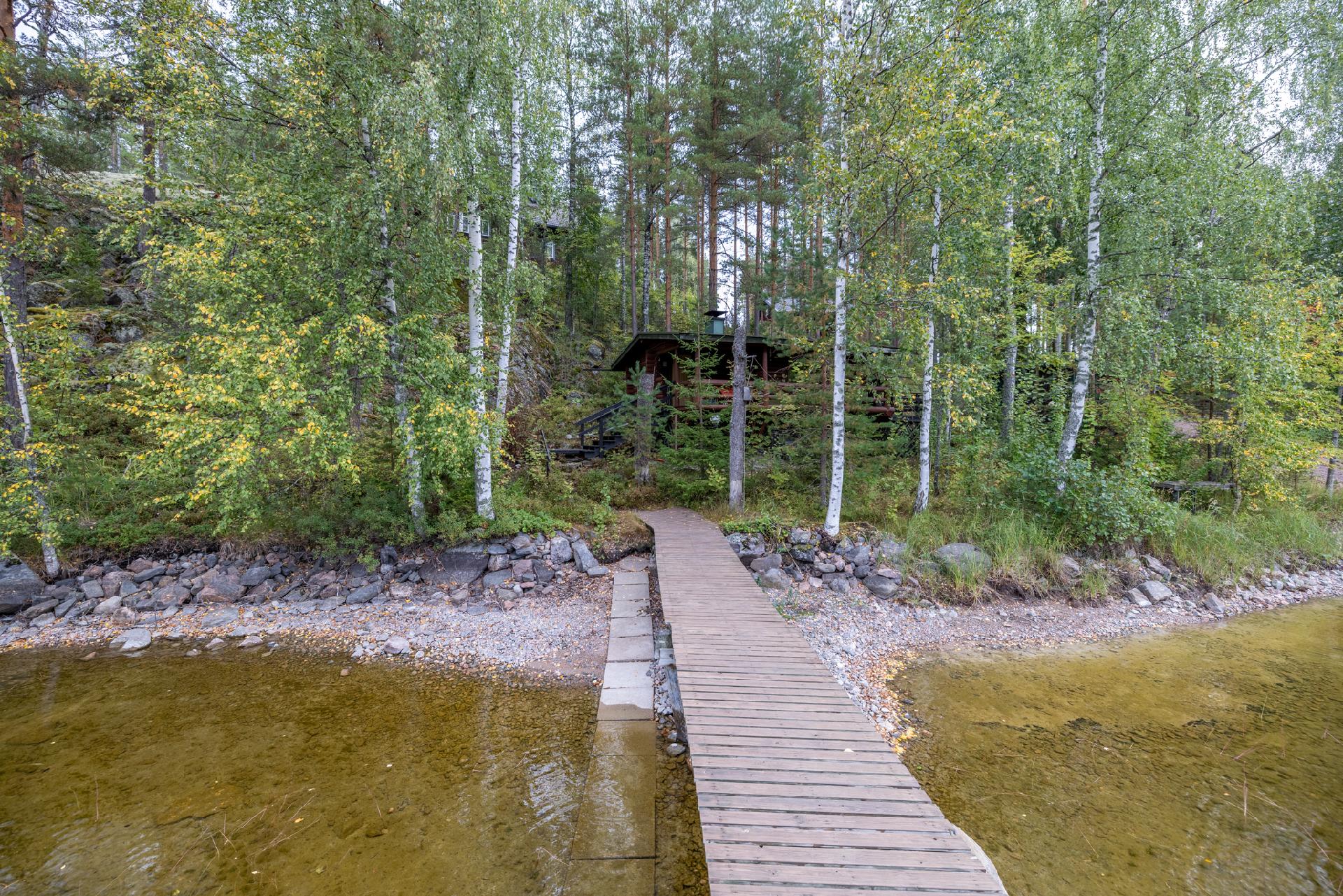 Laiturilta katsottuna alhaalla saunamökki ja mäen päällä päärakennus