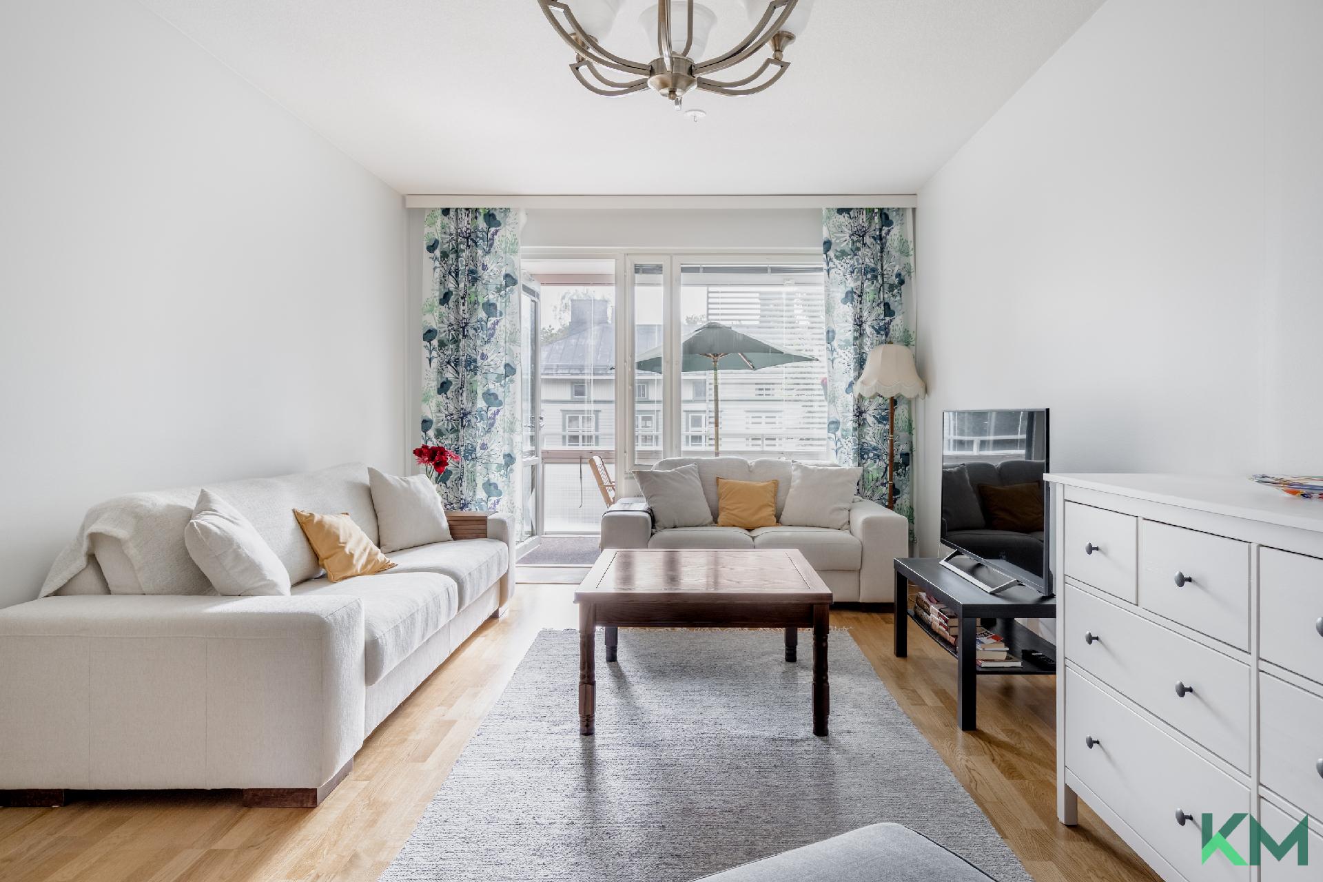 Valoisa olohuone, josta käynti lasitetulle parvekkeelle sisäpihan puolelle.