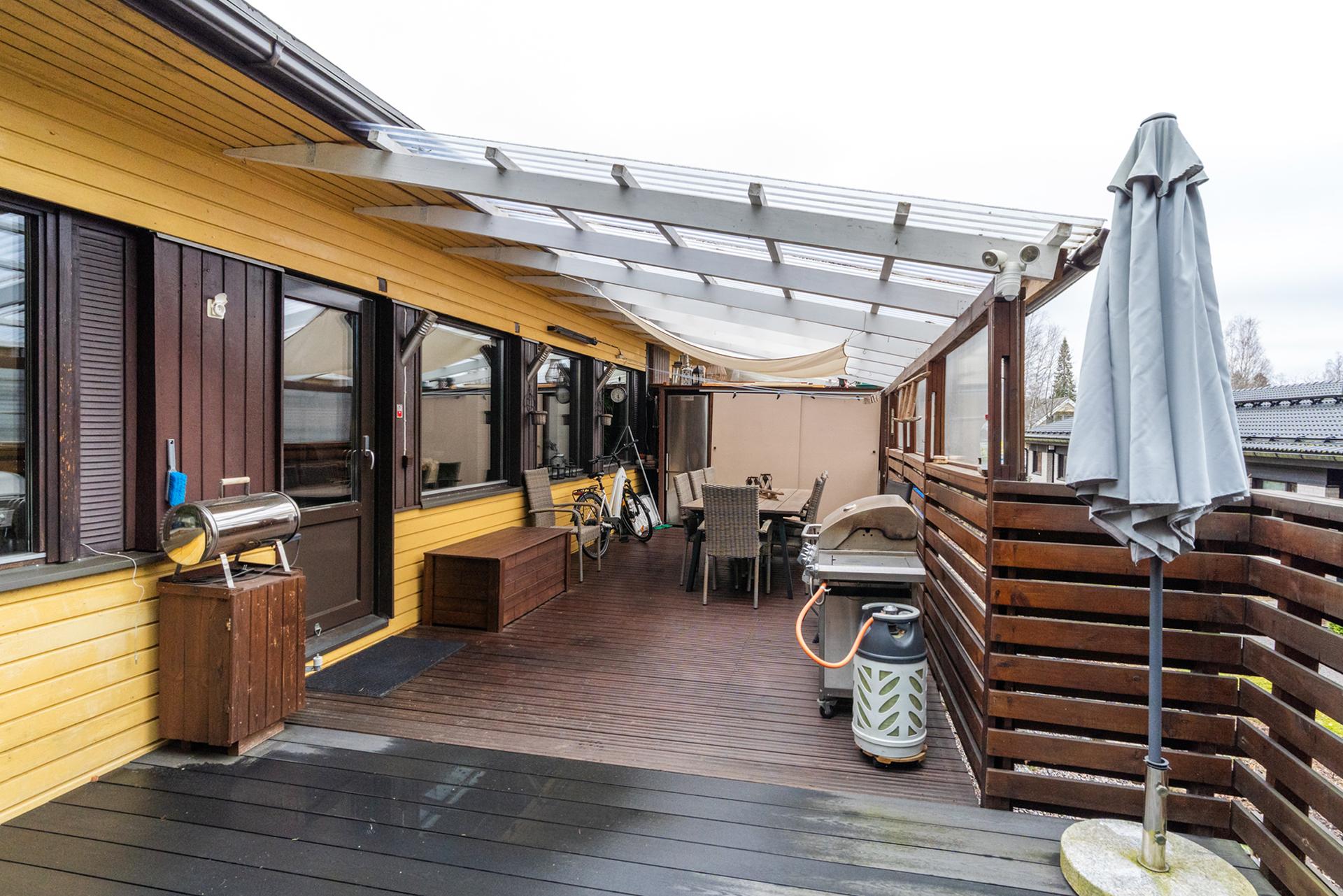 Iso terassi, joka on osittain katettu valokatteella.