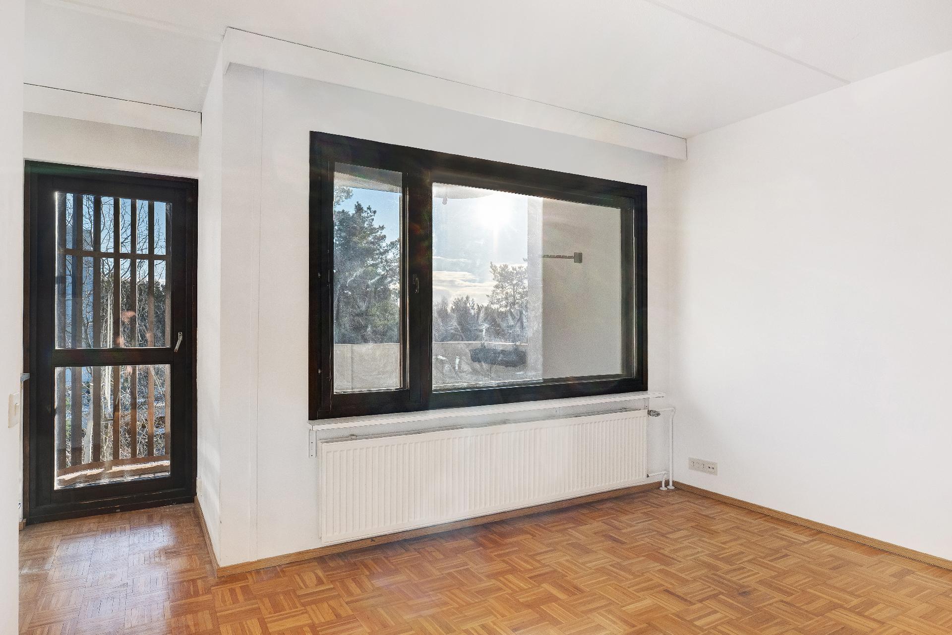 Tumma ikkunanpuitteet ja parvekkeen puuosat antavat kauniin kehyksen maisemalle.