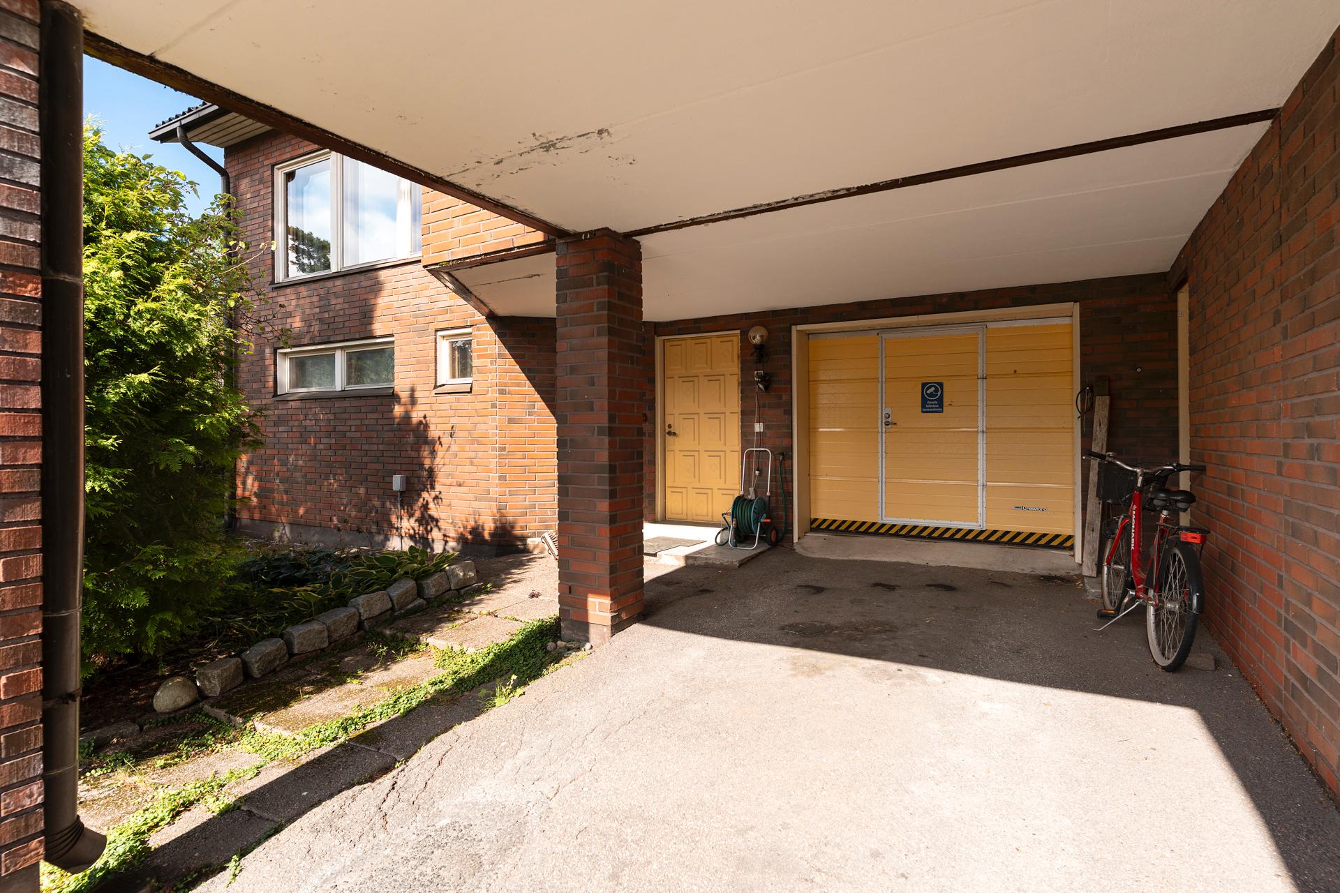 Autotalli ja autokatos sisäänkäynnin vieressä