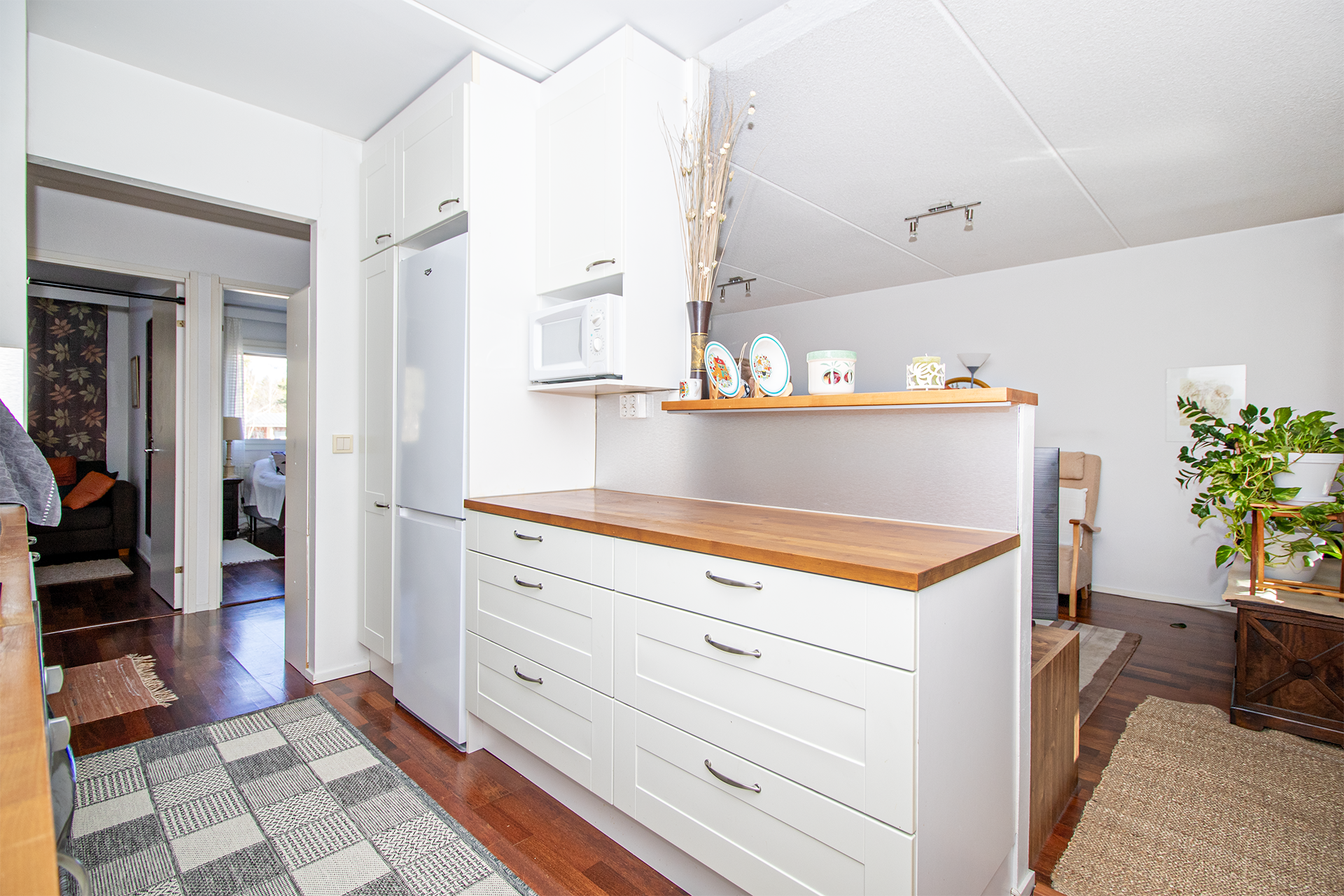 Vaaleansävyisen keittiön ja olohuoneen tilanjakajana saareke luo avaruutta