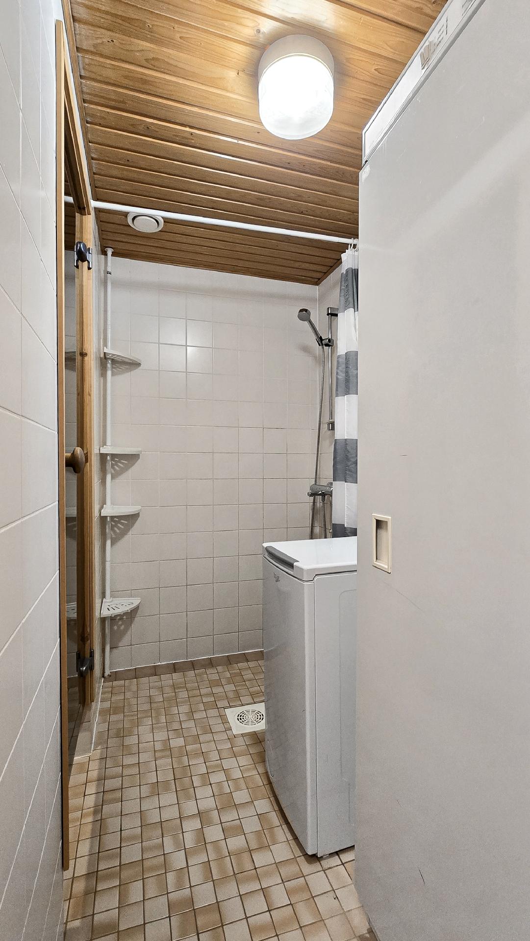 Kylpyhuoneessa pyykinpesukone ja kuivauskaappi