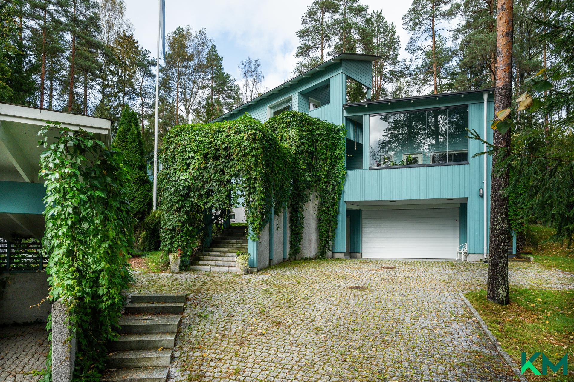 Taloon kuljetaan vehreän pergolan läpi