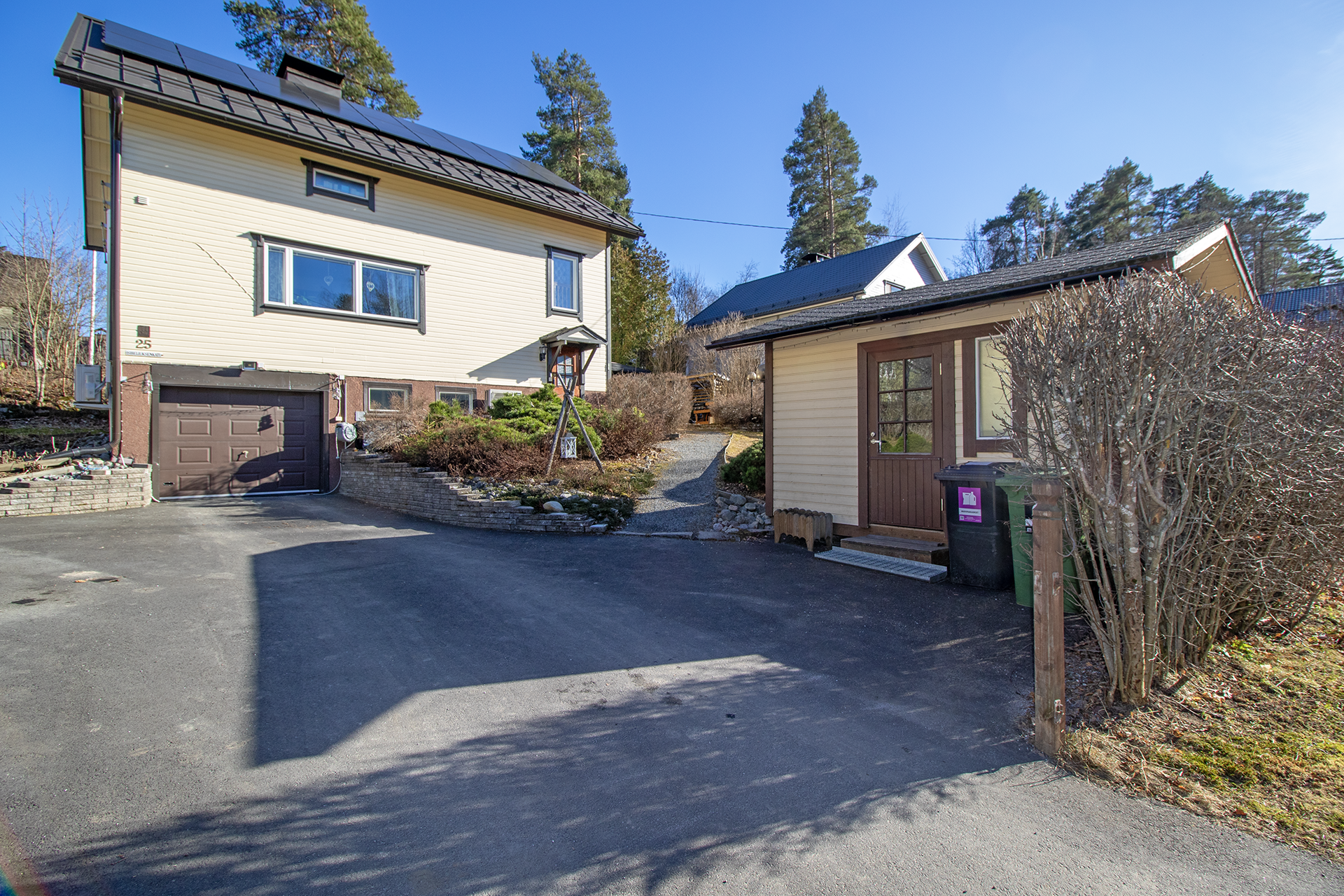 Julkisivu kadulta, asfaltoitu piha ja varasto