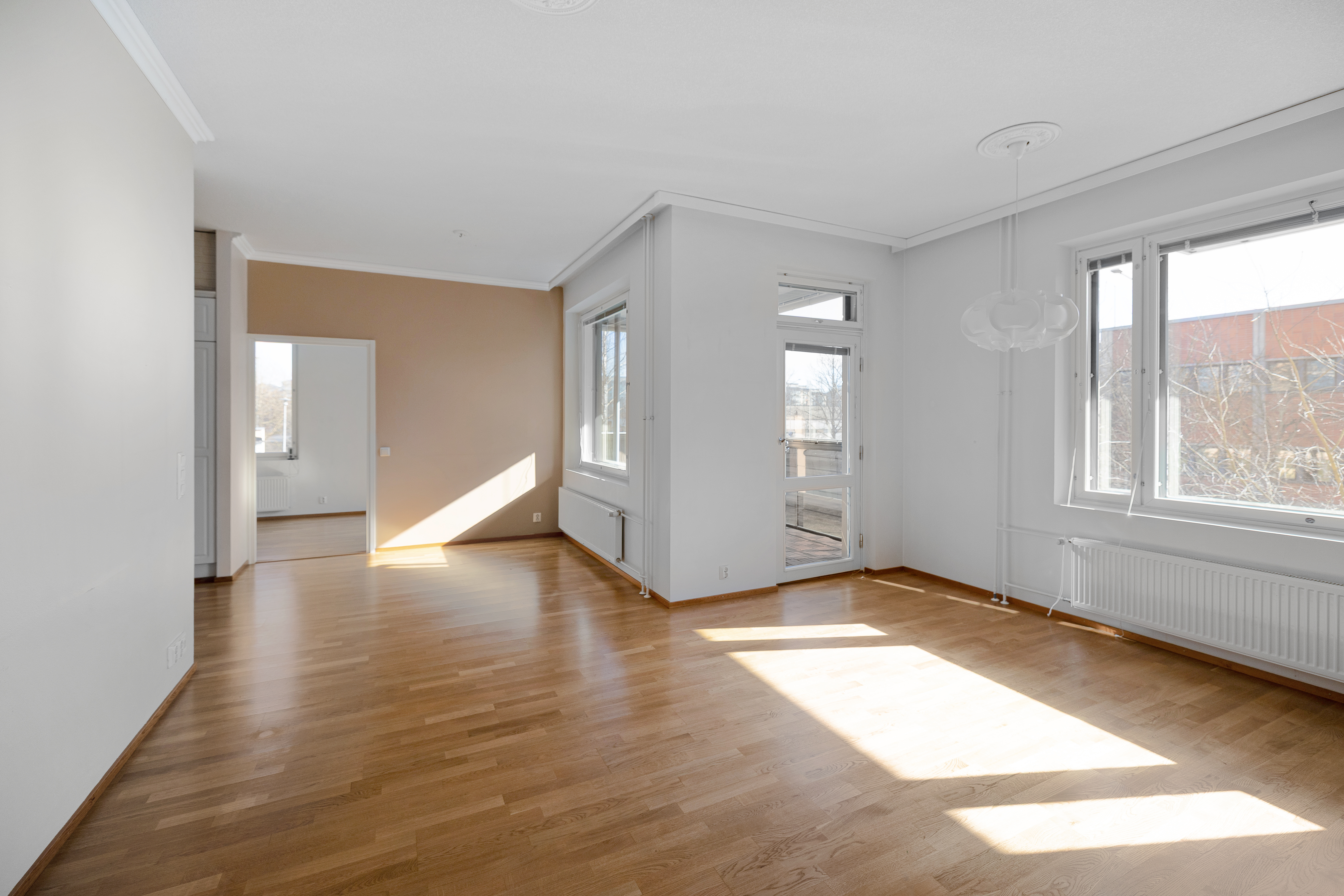 Valoisa olohuone josta käynti lasitetulle parvekkeelle.