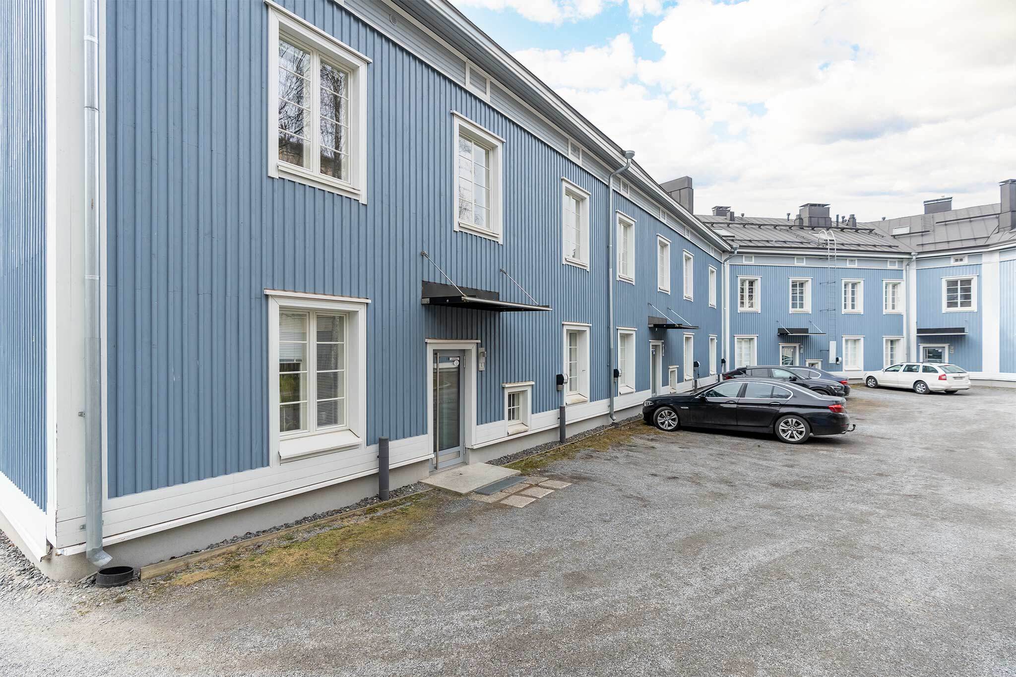 Sisäänkäynti ja taloyhtiön vuokrattavissa olevat autopaikat sisäpihan puolella