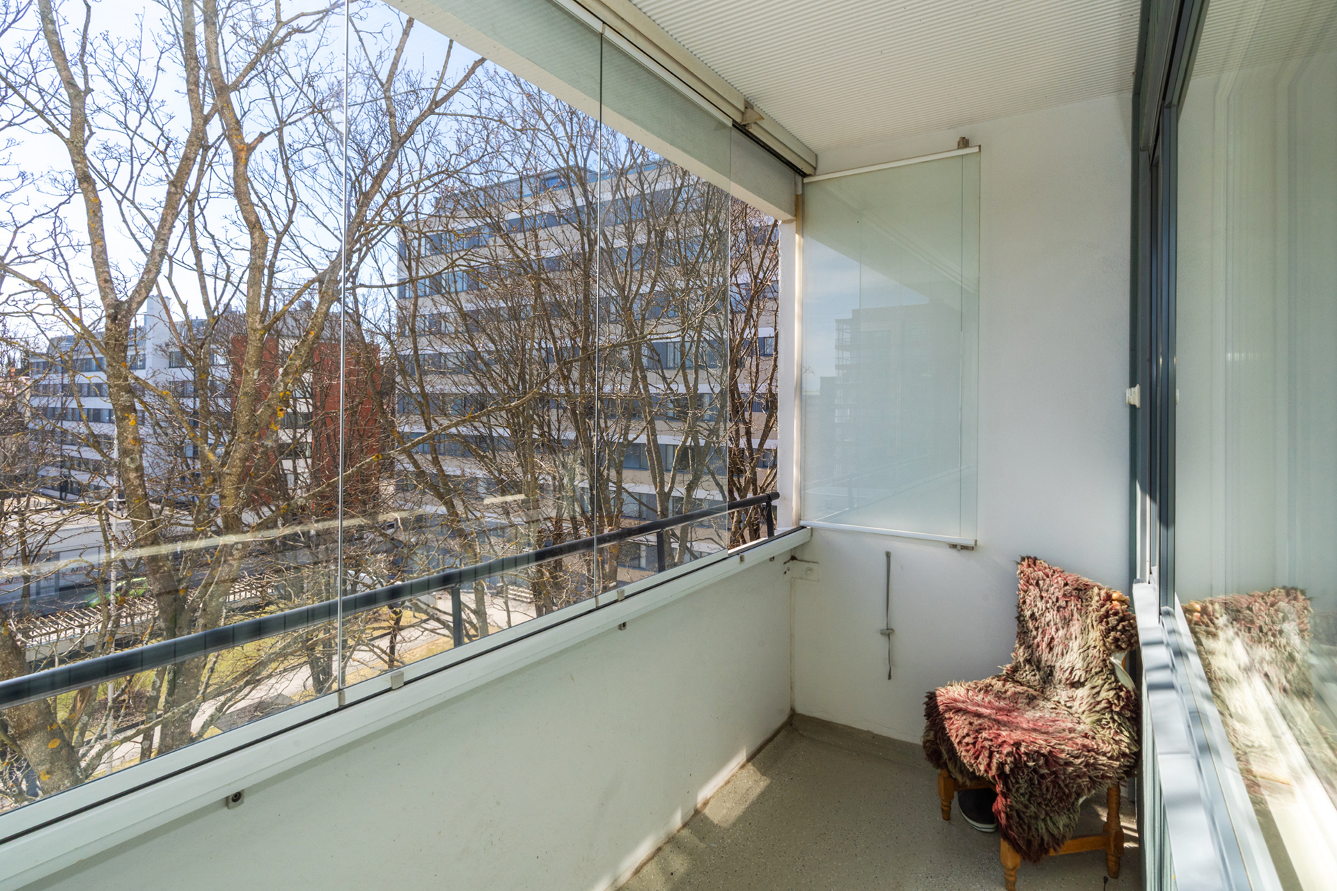 Lasitetulta parvekkeelta on viehättävät näkymät taloyhtiön pihalla ja lehtipuiden latvoihin