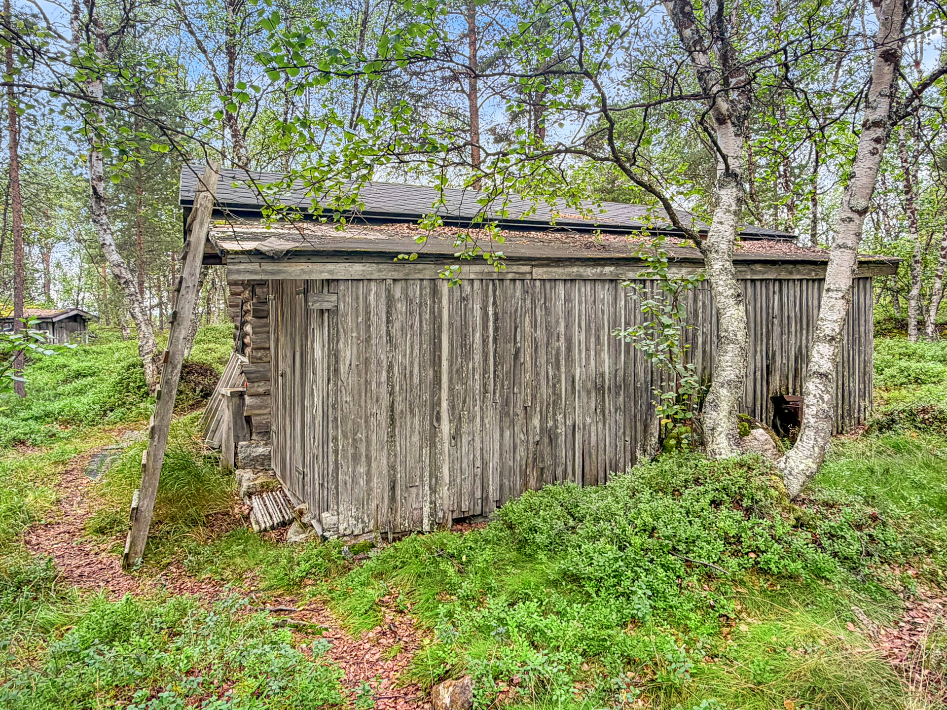 Varastorakennuksen takana purkukuntoinen vaja/ katos