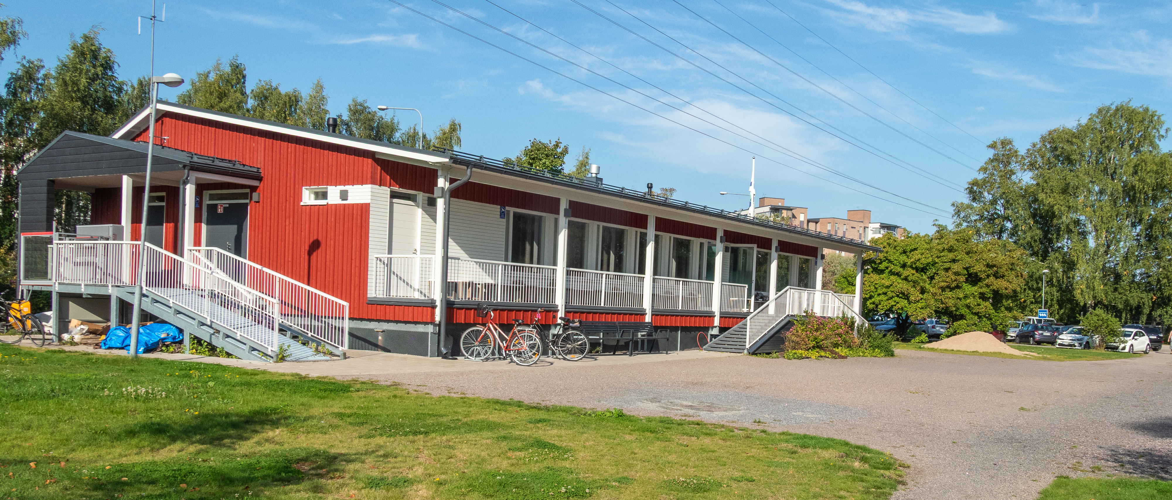 Kerhotalo sijaitsee pääporttien vieressä pysäköintipaikan takana. 